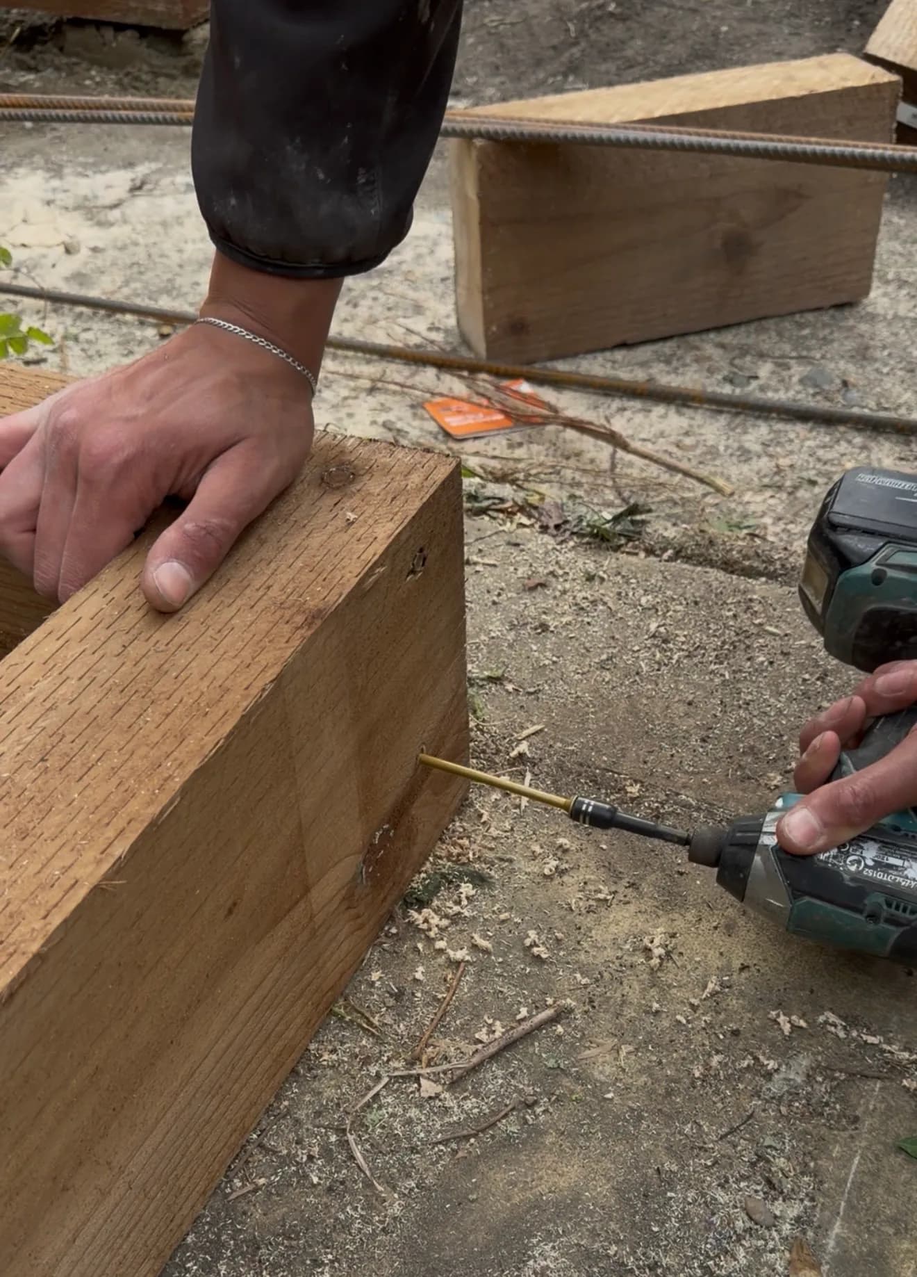 ECH WORKS — Detail of hands drilling into timber during garden construction.
